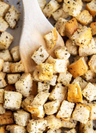 A wooden spatula lifting up some croutons.