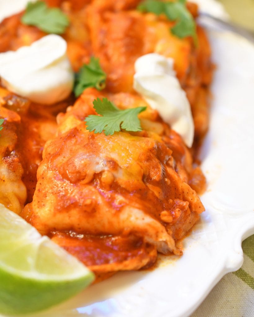 Close up view of slow cooker pork enchiladas on a white plate.