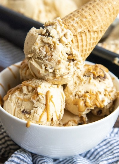 A bowl of peanut butter ice cream, with peanut butter swirls, and peanut butter cups.