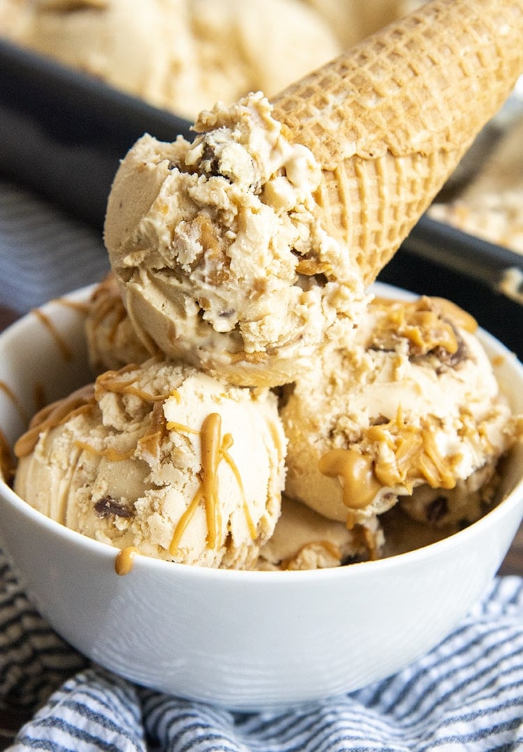 A bowl of peanut butter ice cream, with peanut butter swirls, and peanut butter cups.