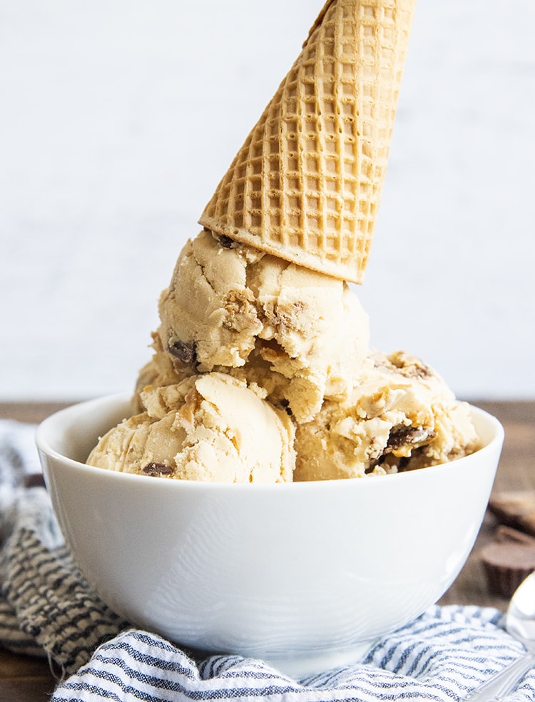 A bowl of peanut butter ice cream topped with an upside down ice cream cone.