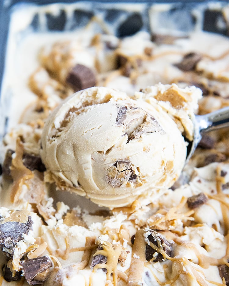 A scoop of peanut butter cup ice cream in a pan of peanut butter ice cream.