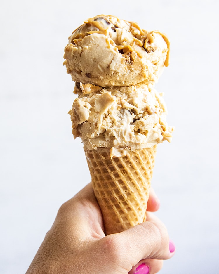An ice cream cone full of two scoops of peanut butter ice cream.