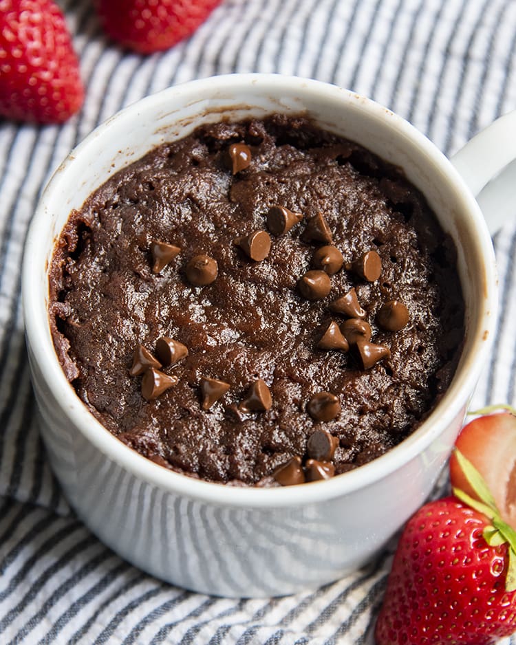 A chocolate brownie in a mug with chocolate chips on top