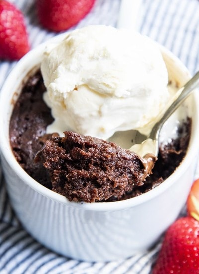 A bite of mug brownie on a spoon with vanilla ice cream on top