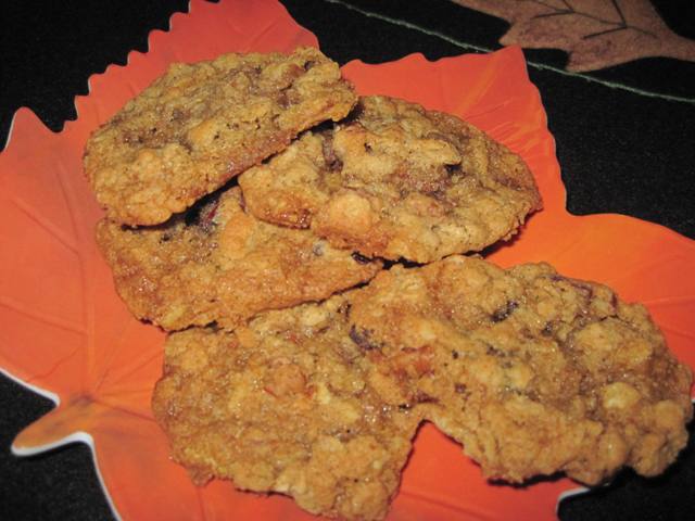 Angled view of oatmeal cranraisin pecan cookies on a orange plate.