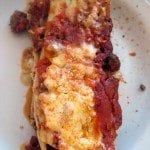Close up view of three cheese manicotti on a white plate.