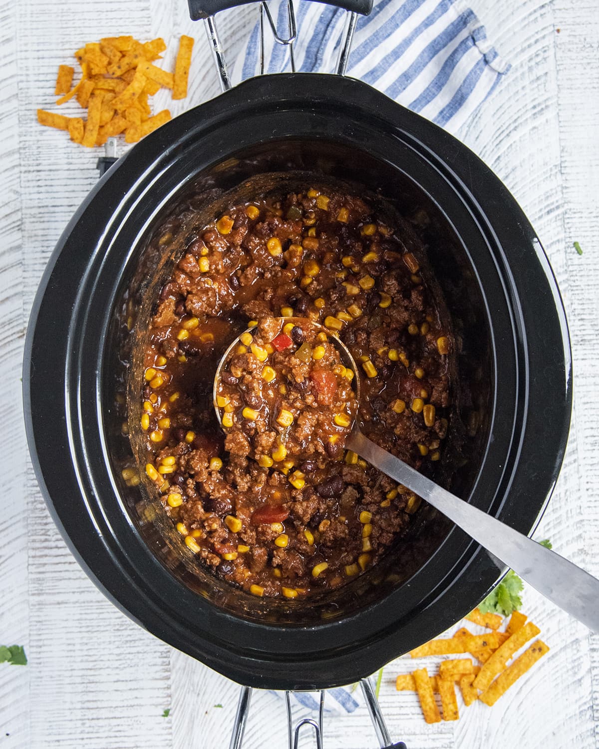 An overhead photo of a crock pot full of taco soup with a ladle of soup in it.