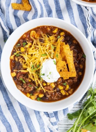 An overhead photo of a bowl of taco soup with sour cream and cheese on top.