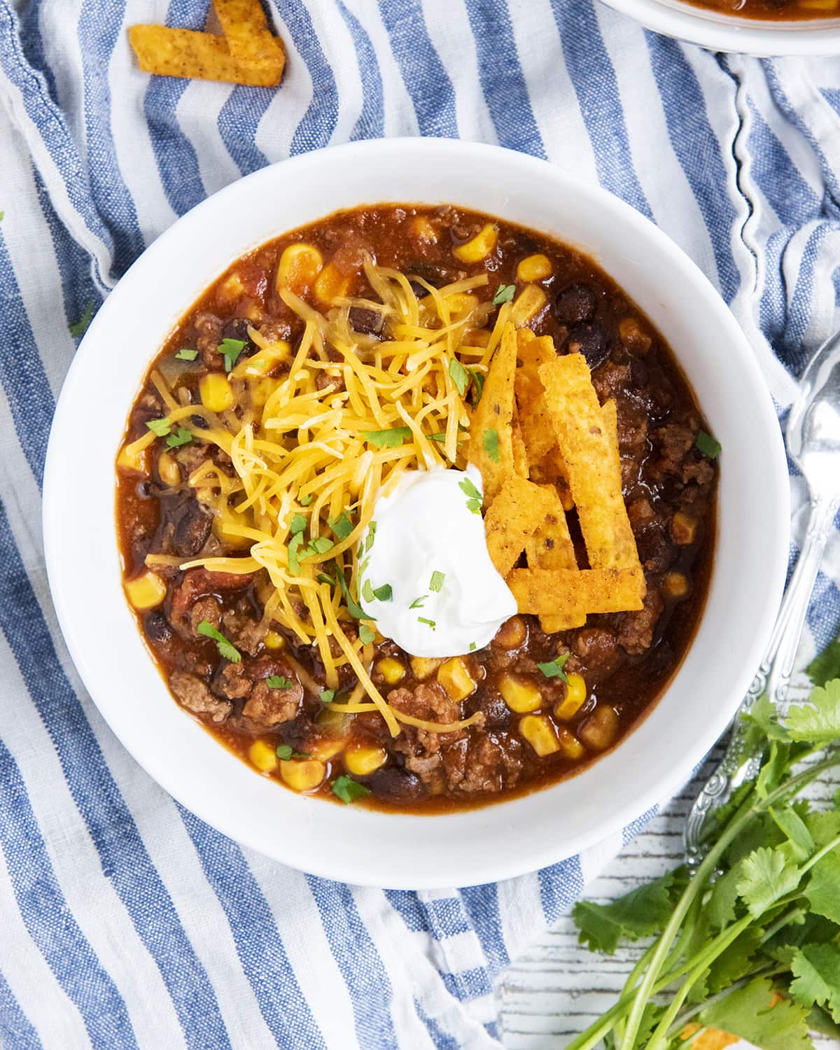 An overhead photo of a bowl of taco soup with sour cream and cheese on top. 