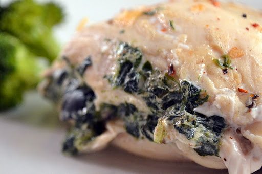Close up view of olive and spinach stuffed chicken on a white plate.