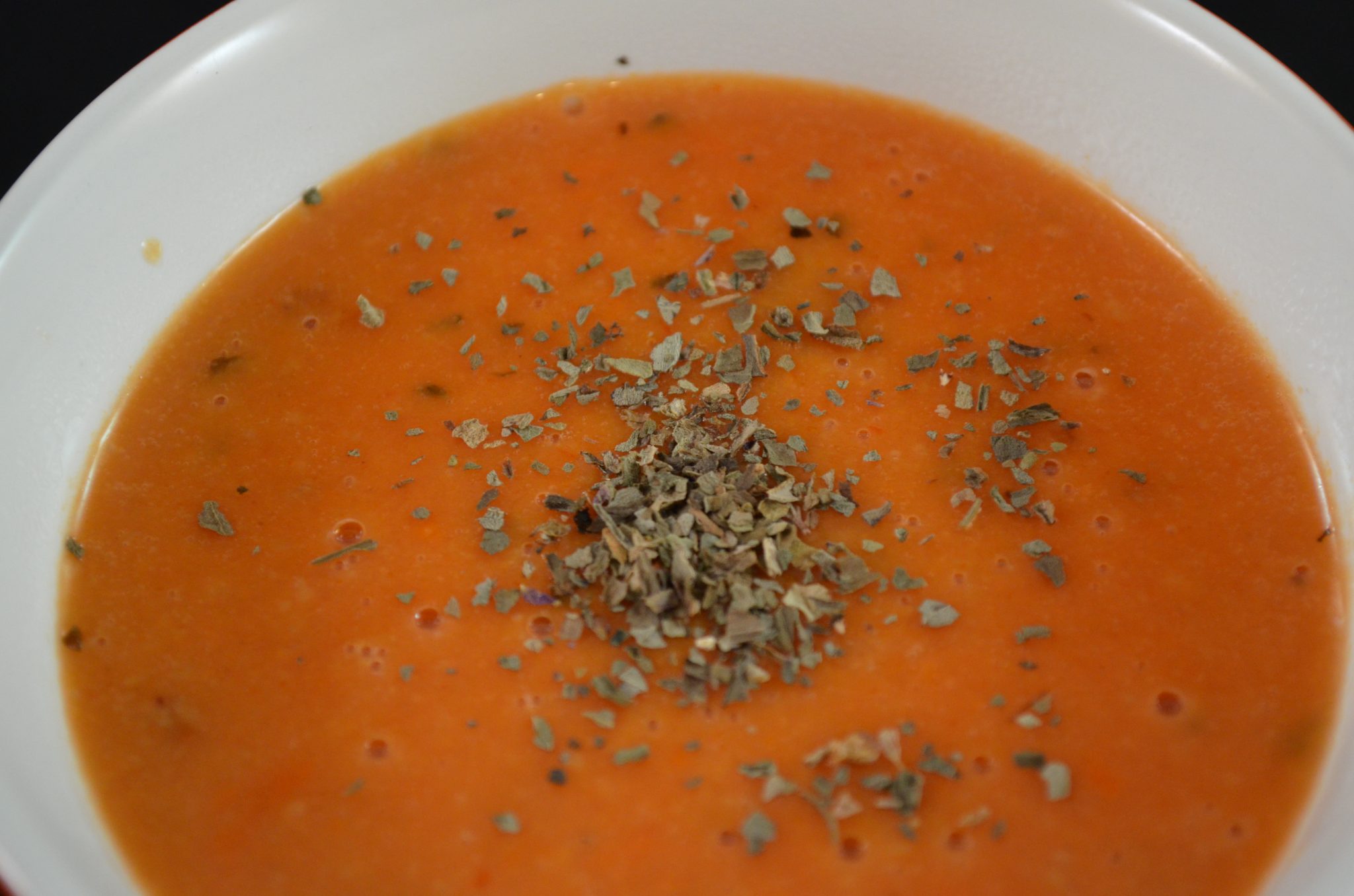 Close up view of creamy parmesan tomato basil coup in a bowl.