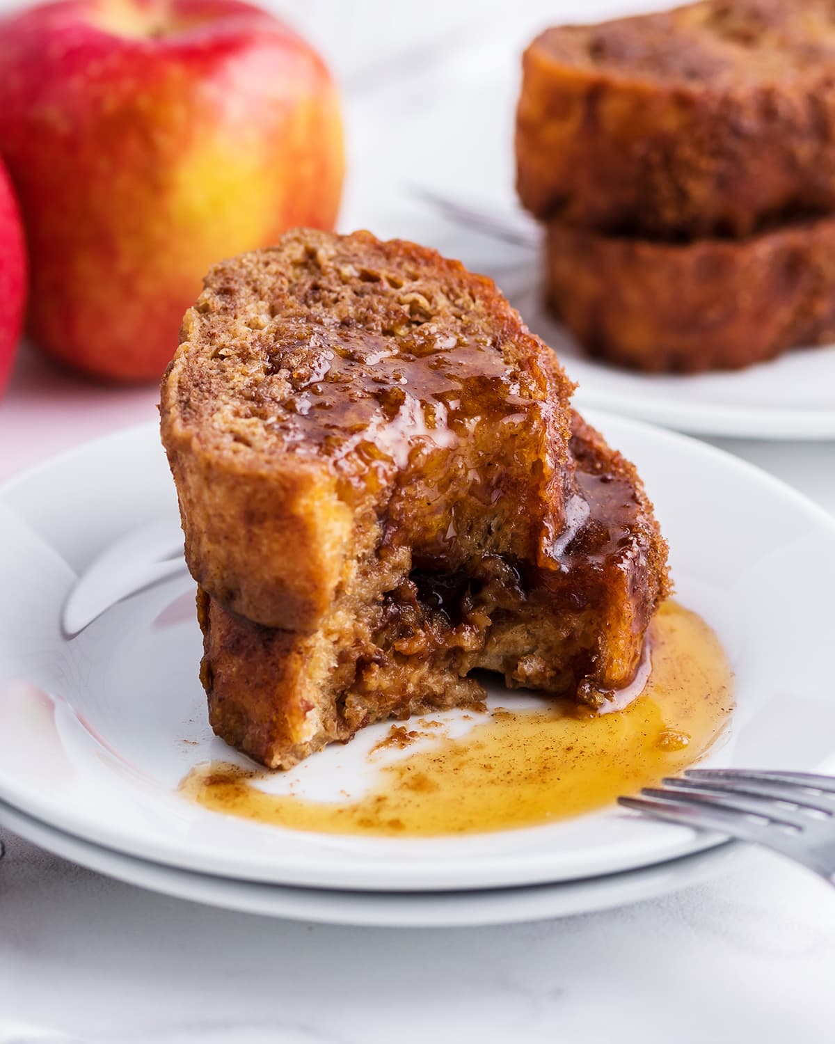A plate of two stacks of french toast, topped with syrup and with bites out of them.