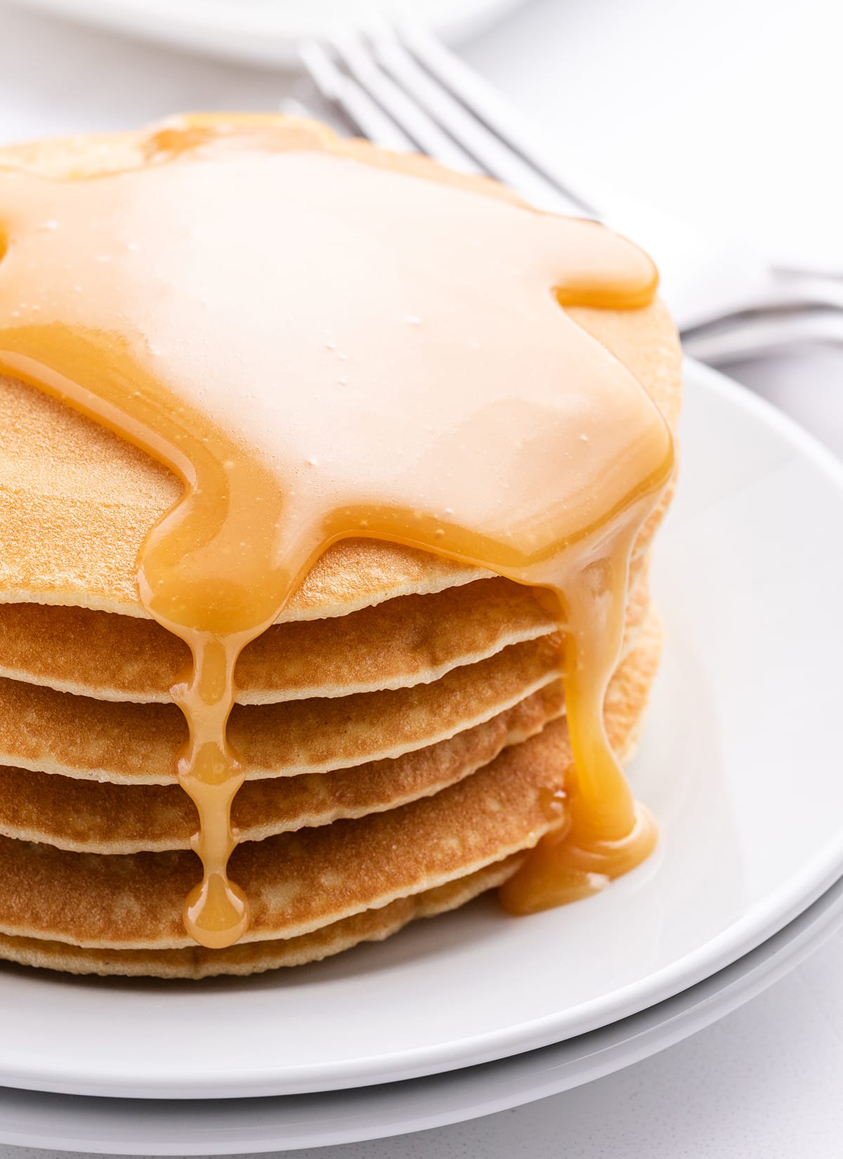 A close up of a stack of pancakes topped with buttermilk syrup. 
