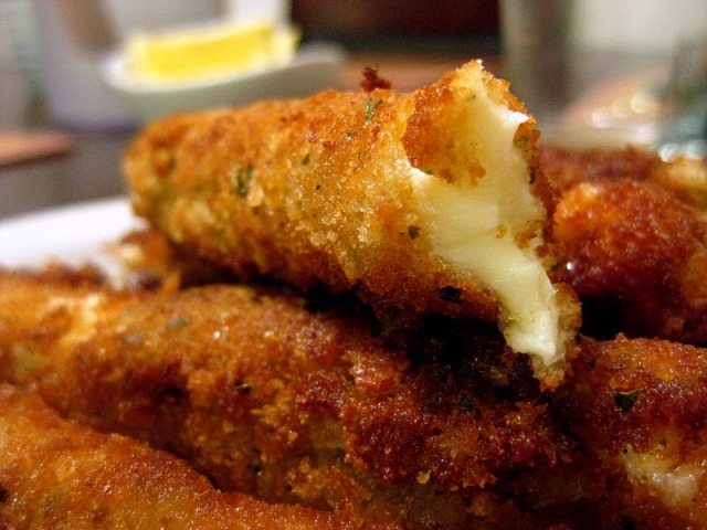 Close up of mozarella sticks on a white palte.