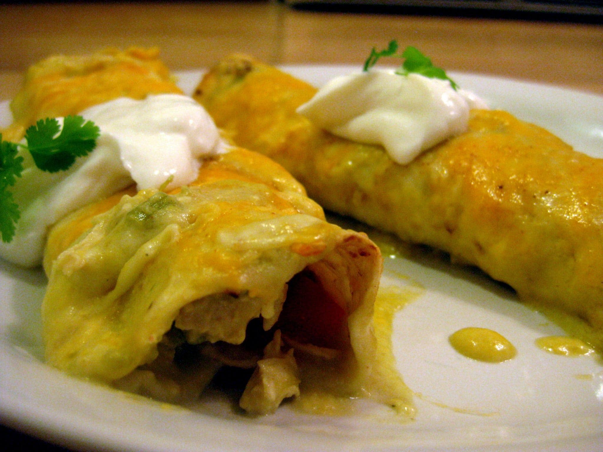 Angled view of enchiladas verdes on a white plate.