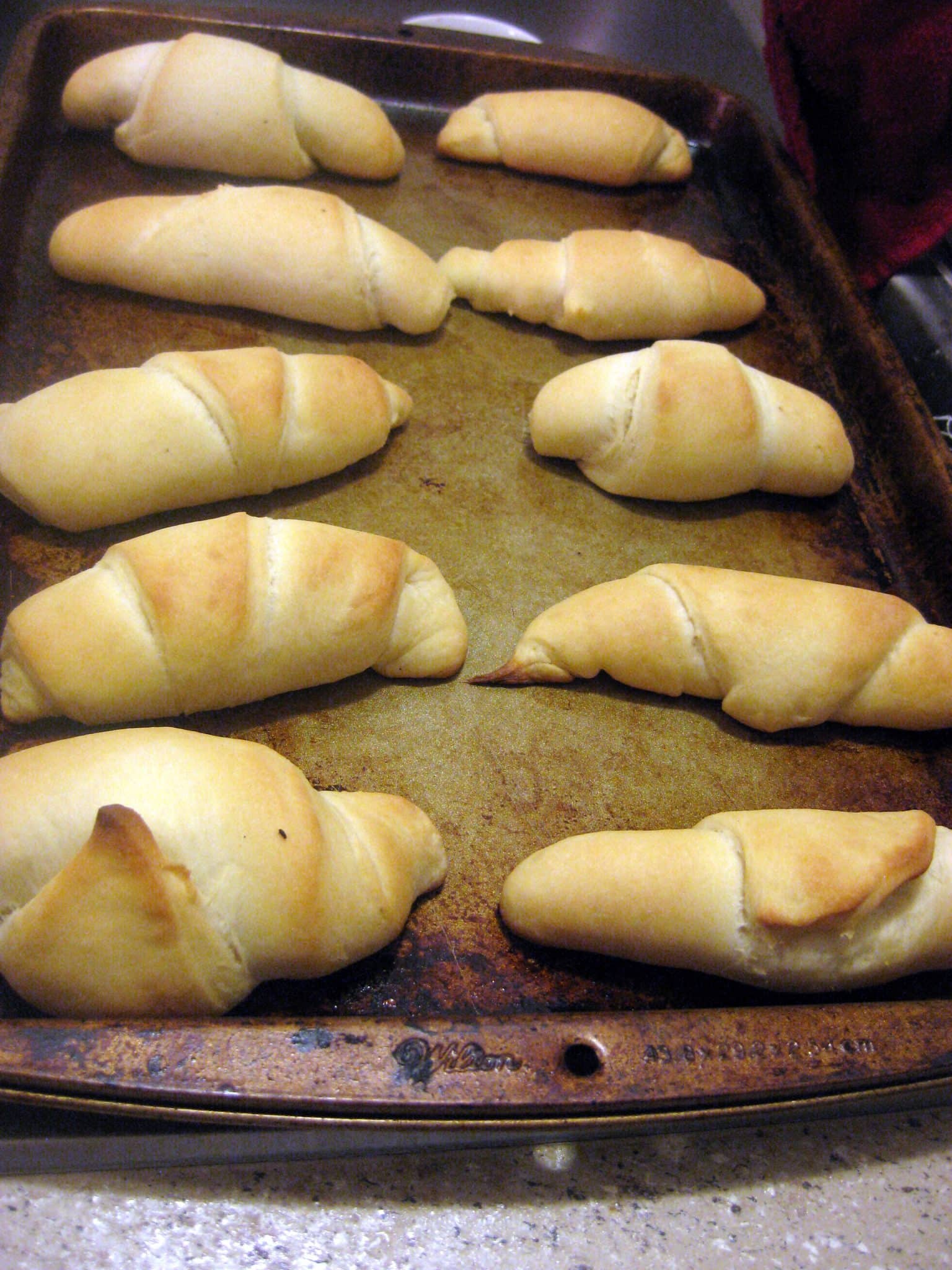 Angled view of crescent rolls on a baking pan.