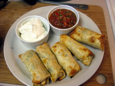 Top view of a plate of southwestern rolls with sour cream and salsa.
