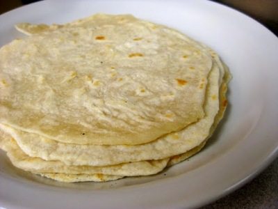 A stack of tortillas on a white plate.