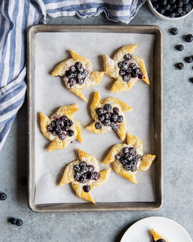 An above photo of Puff pastry blueberry danishes on a cooking sheet.
