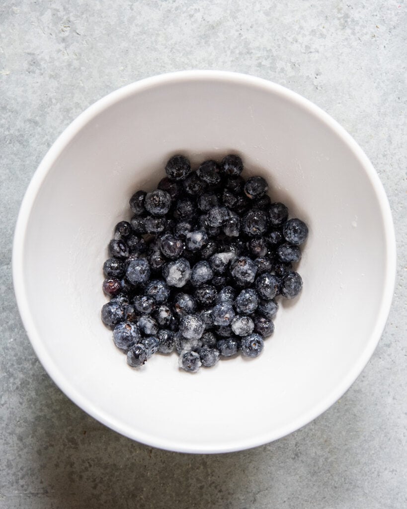 A bowl of blueberries mixed with granulated sugar.