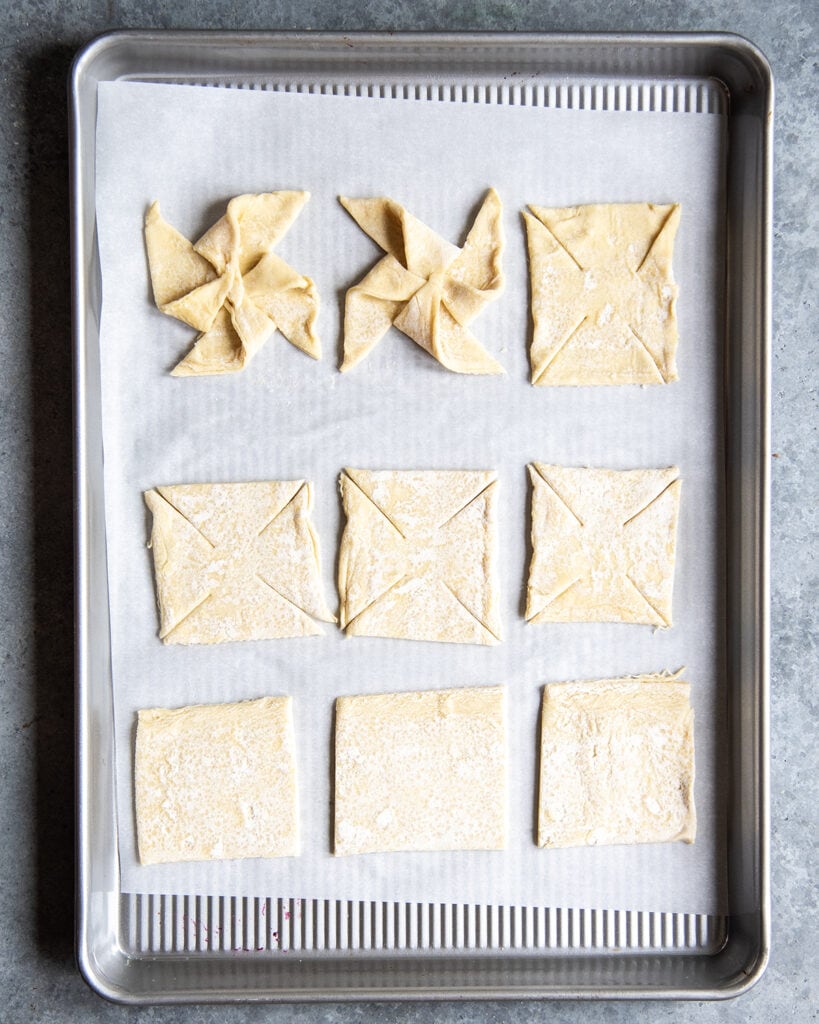 Square pieces of puff pastry cut into triangles and shaped into pinwheels.