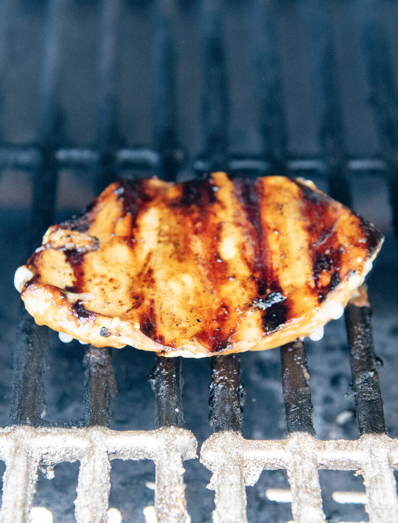 A piece of chicken breast cooking on a grill.