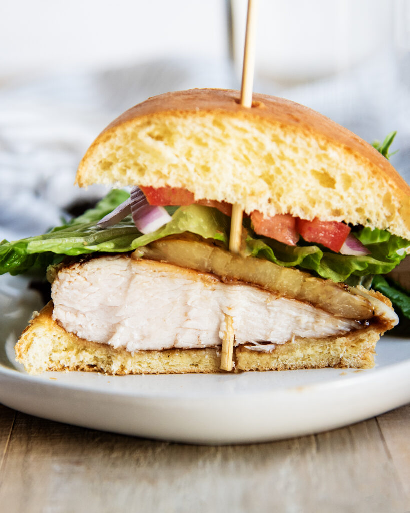 A teriyaki chicken sandwich cut in half showing the middle of the chicken breast.