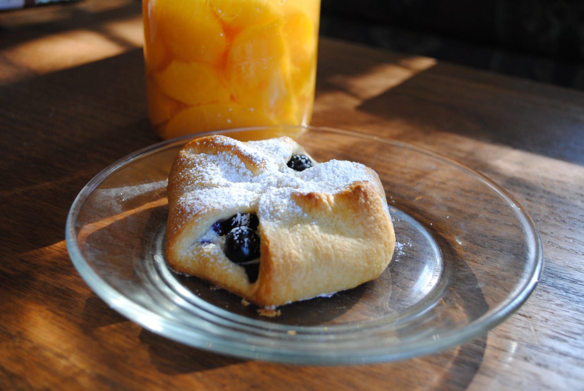 Angled view of a blueberry danish with peaches in the back.
