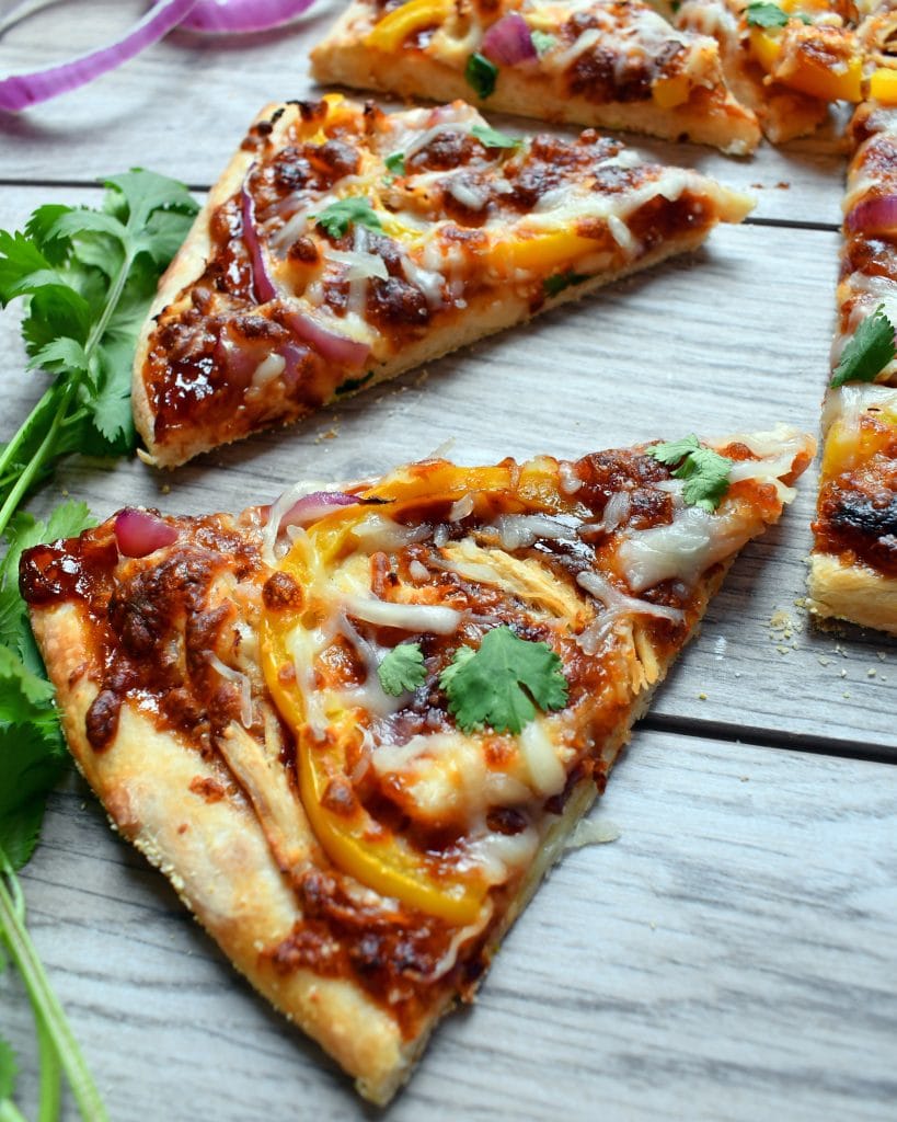 Close view of bbq chicken pizza on a wood board.