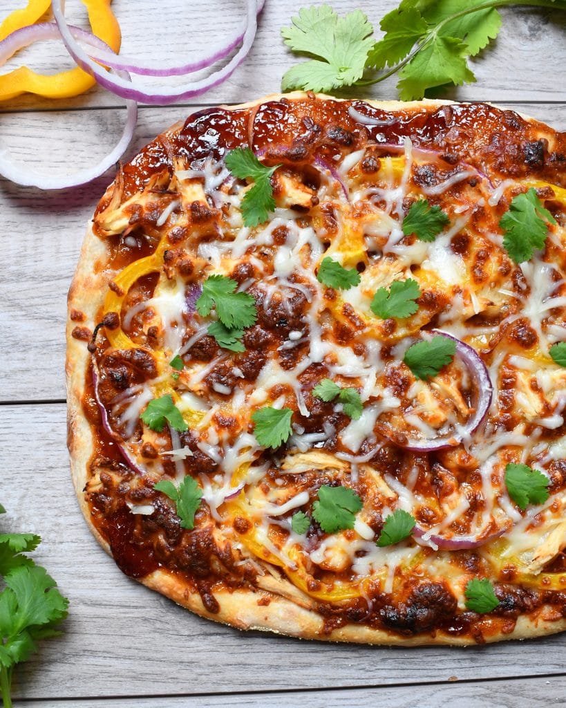 Top view of bbq chicken pizza on a wood board.