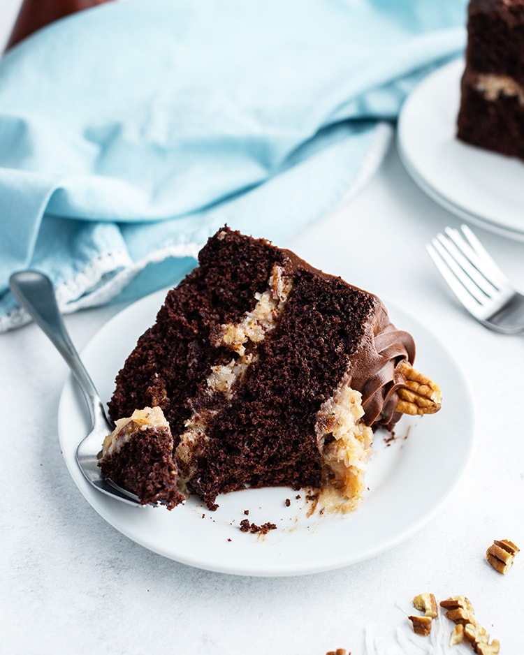 A slice of German chocolate cake with a bite taken out of it.