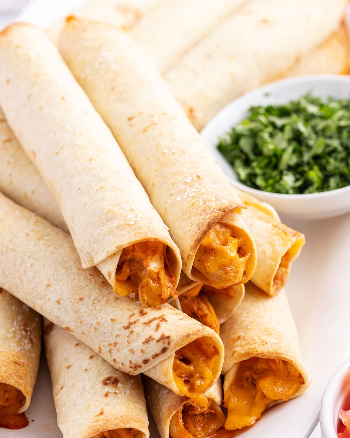 A close up of creamy chicken taquitos in a pile. 