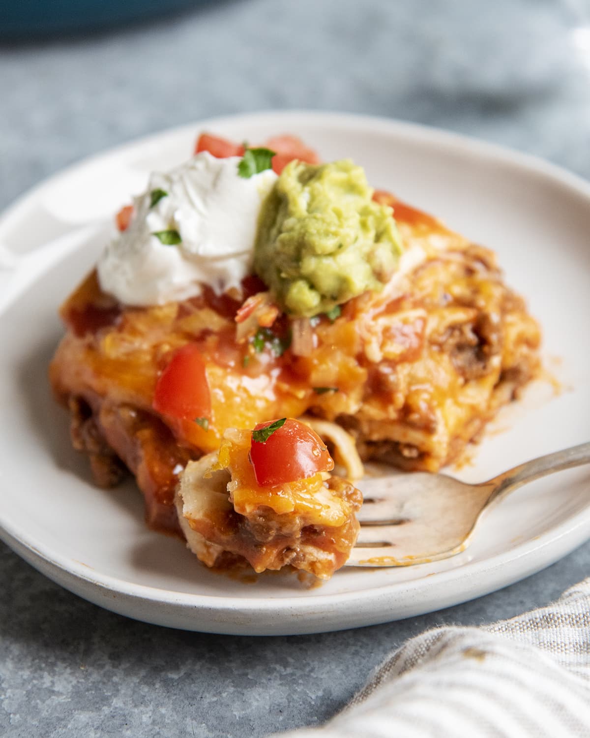 A fork cutting off a bite of dutch oven enchilada casserole.