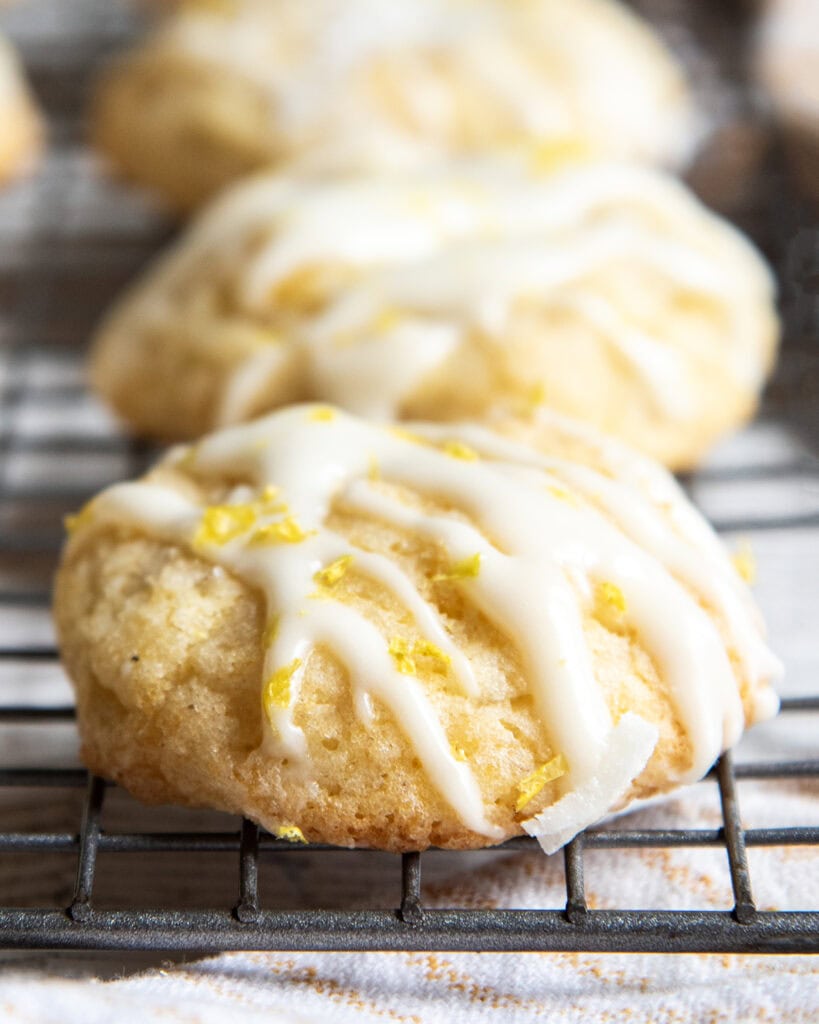 A row of yellow cookies on a cooling rack topped with a white glaze.