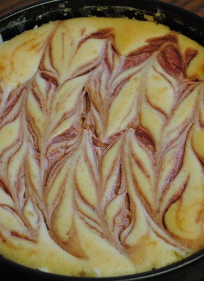 Top view of swirled strawberry and chocolate cheesecake in a baking pan.