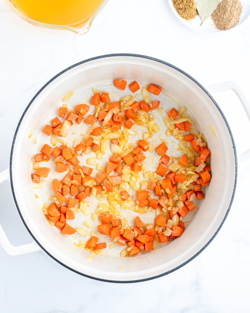 A pot of sauteed onion and carrots. 