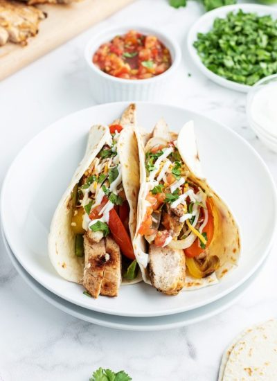 A small plate of two flour tortillas loaded with chicken fajitas.