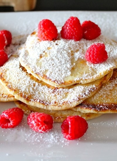 Top view of lemon ricotta pancakes on a white plate.