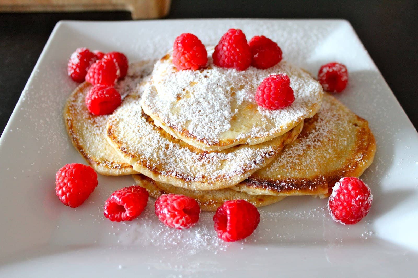 Top view of lemon ricotta pancakes on a white plate.