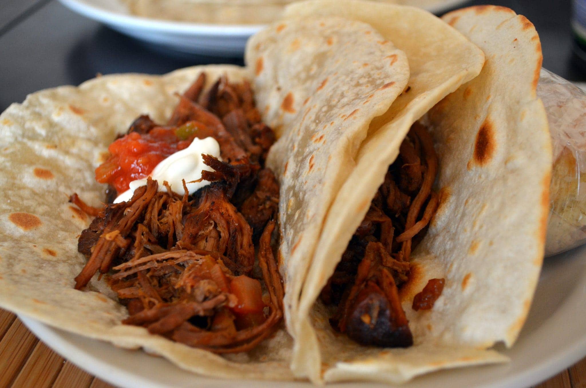 Close up view of shredded beef tacos in tortillas.