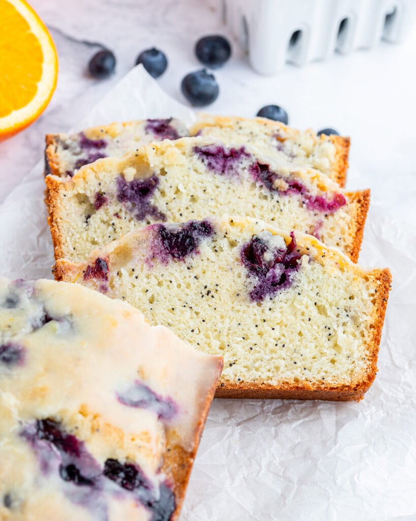 Slices of blueberry poppy seed bread laying on a piece of parchment paper. 