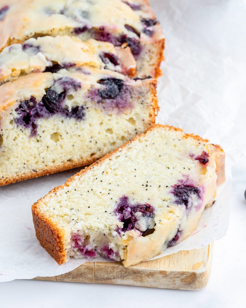 A piece of blueberry poppy seed bread with a bite out oif it.