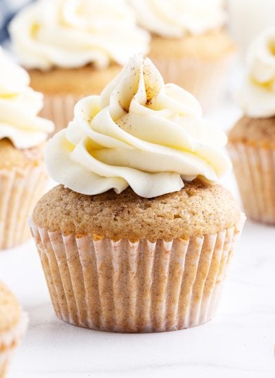 A close up of a cupcake topped with a white buttercream and sprinkled with cinnamon.