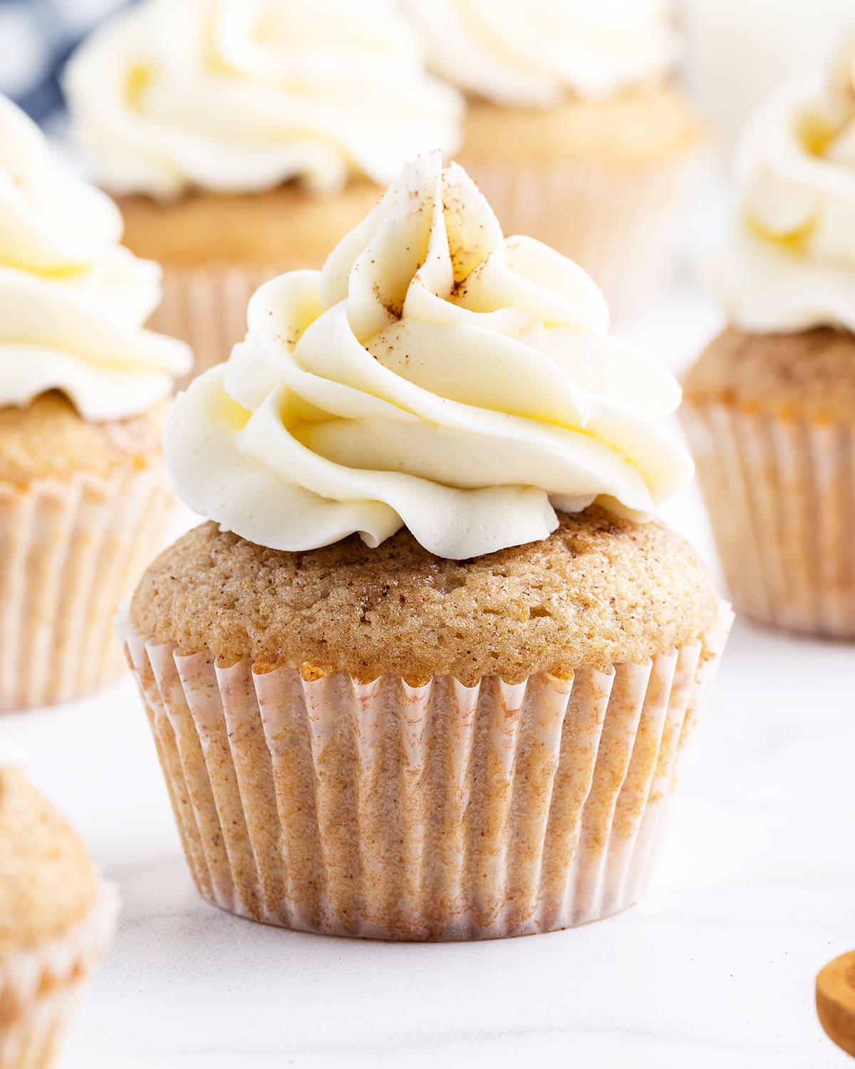 A close up of a cupcake topped with a white buttercream and sprinkled with cinnamon.