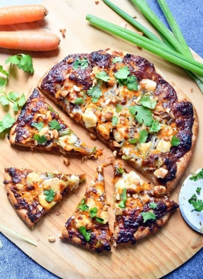 Top view of thai chicken pizza on a wooden board.