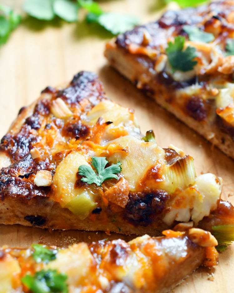 Close up view of thai chicken pizza on a wooden board.