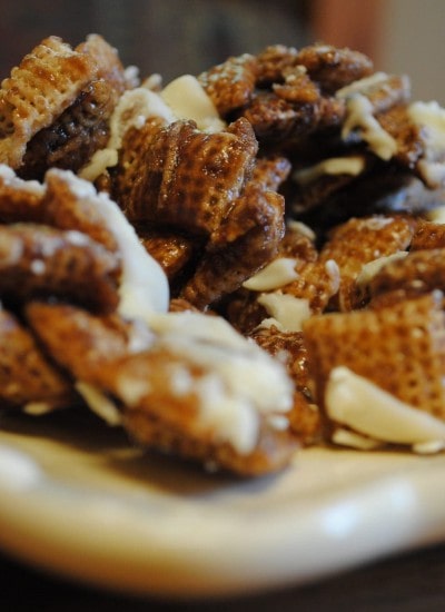 Close up view of chocolate caramel chex mix on a white plate.