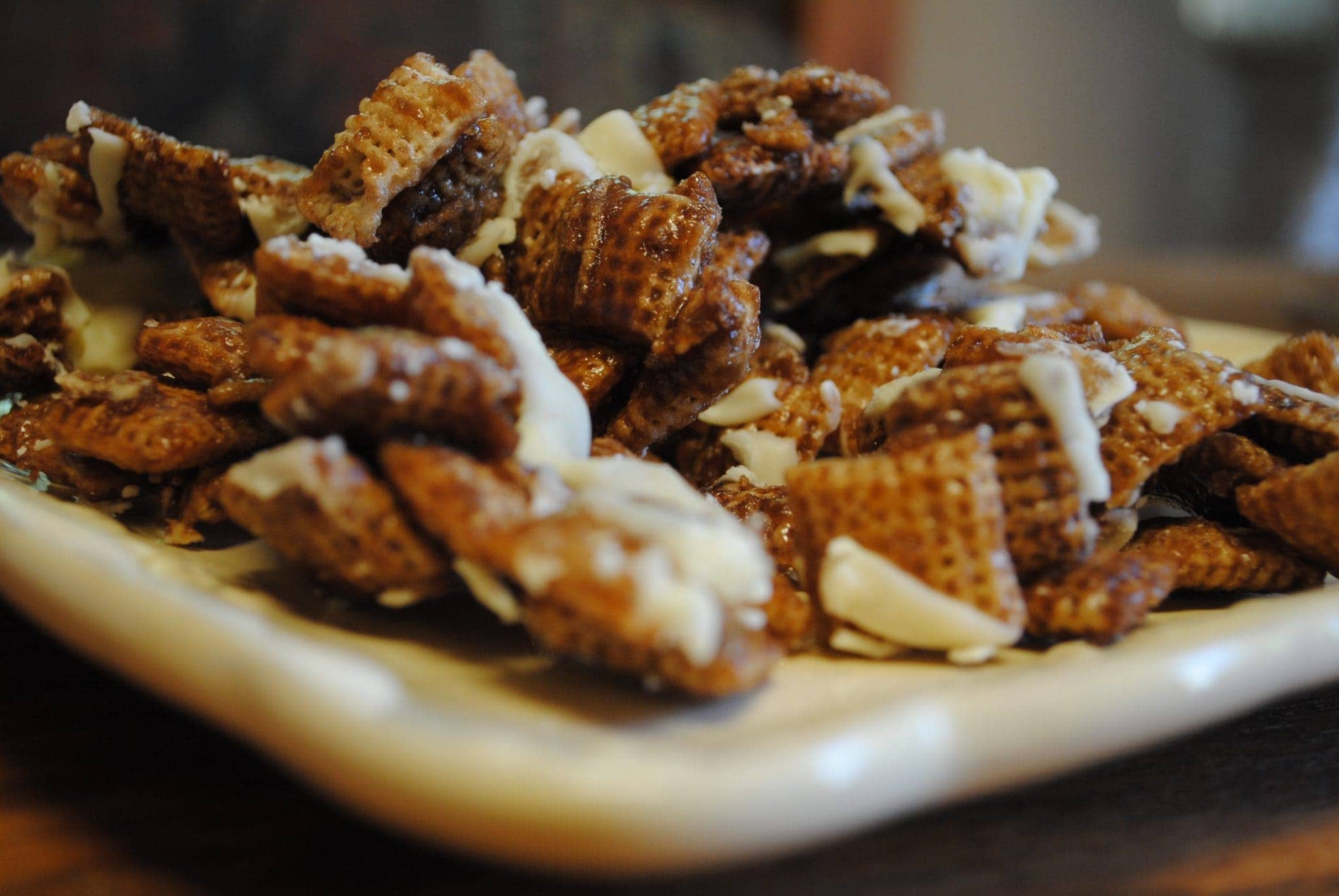 Close up view of chocolate caramel chex mix on a white plate.
