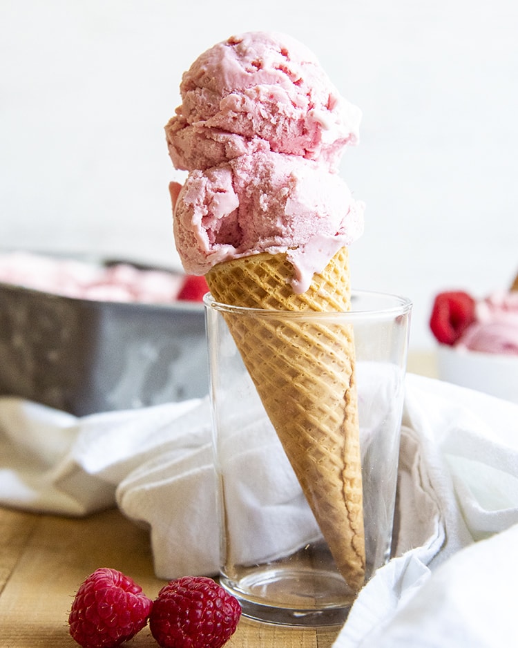 An ice cream cone topped with two scoops of raspberry ice cream.